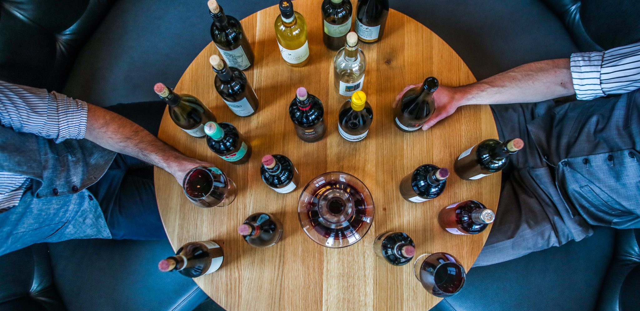 alt="Wine bottles on round table view from above"