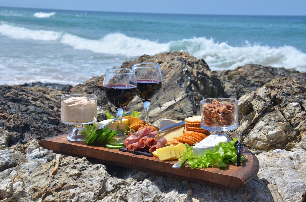 Cheese platter with wine at ocean side rocks